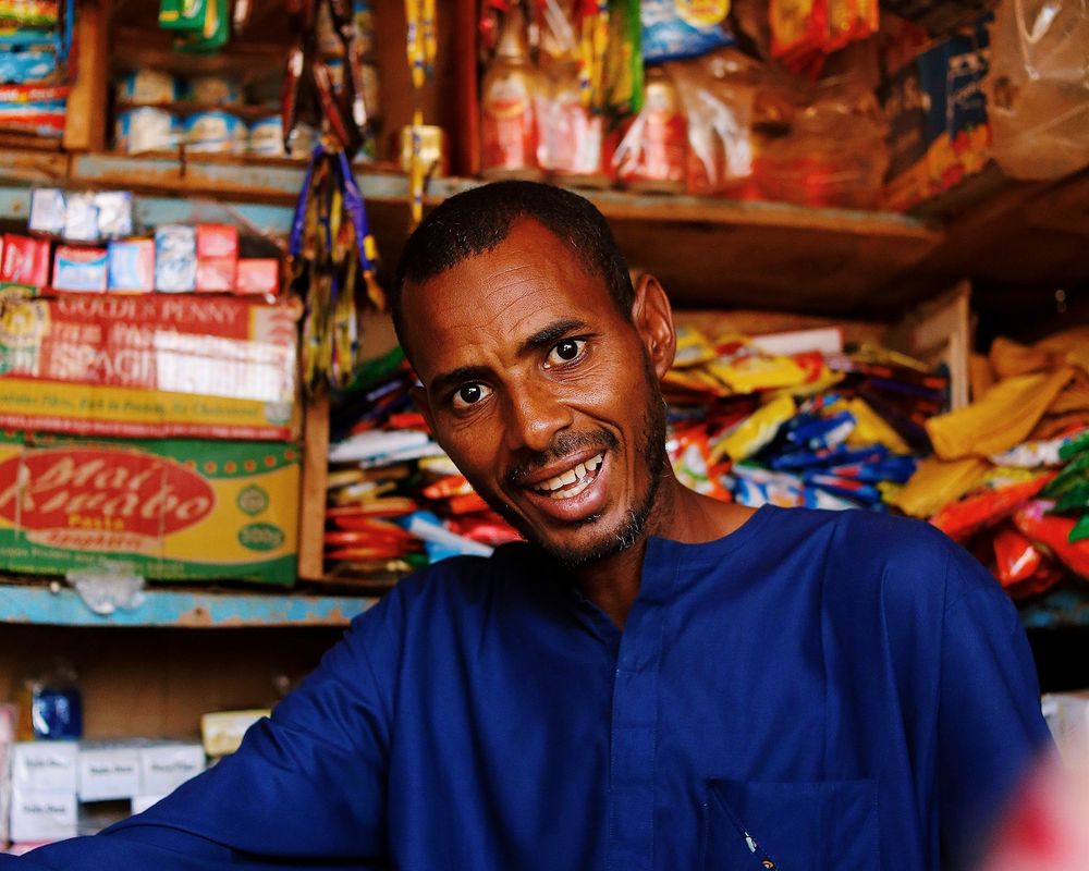 Nigerian shopkeeper in a stocked neighborhood shop